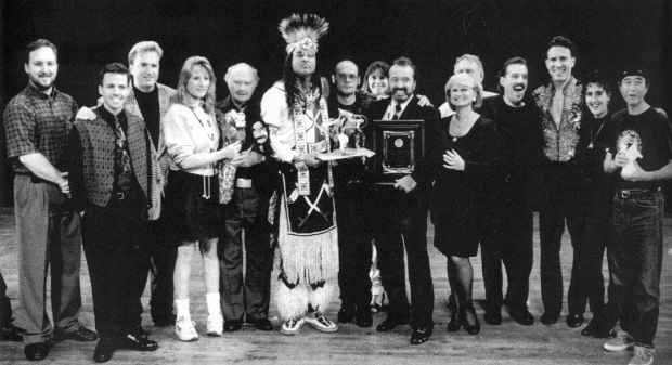 Public Show lineup (l-r) Mark McGuire, David Deeble, Dan Benneett, Ginny Rose, Art Jennings, Dallas Chief Eagle, Karl Heinz Ziethen, Bob & Peggy Bramson, Dick Franco, Albert Lucas, Noelle Franco, Koma Zurz at the 1996 IJA Festival in Rapid City, SD.